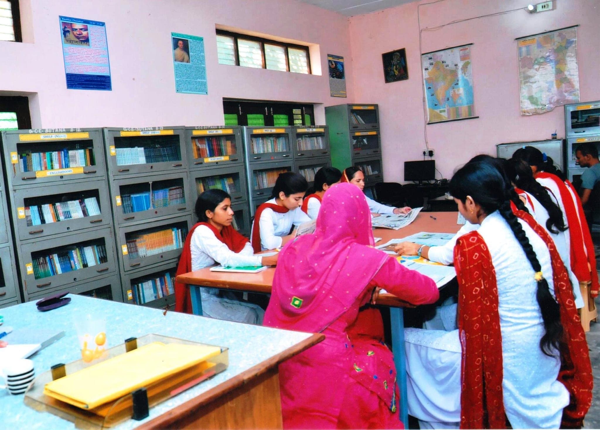 Library reading room, students at the table by the subject-wise shelves
